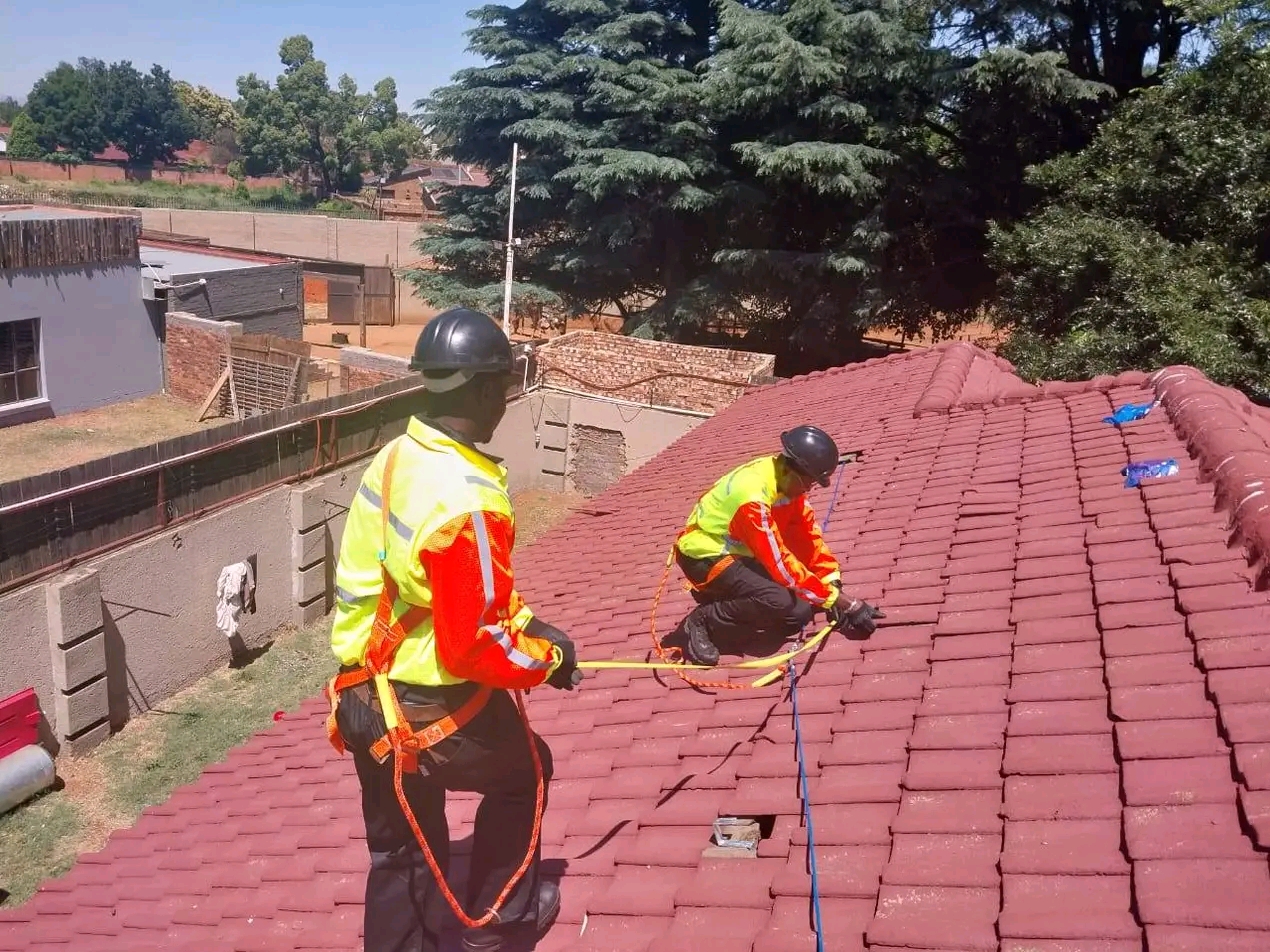 Roof team in safety harnesses running cabling for a solar installation